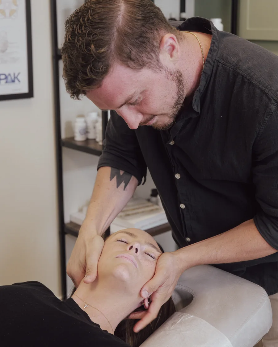 Fort Myers chiropractor Dr. Jarod Ward cradling a patient's head during a cervical adjustment