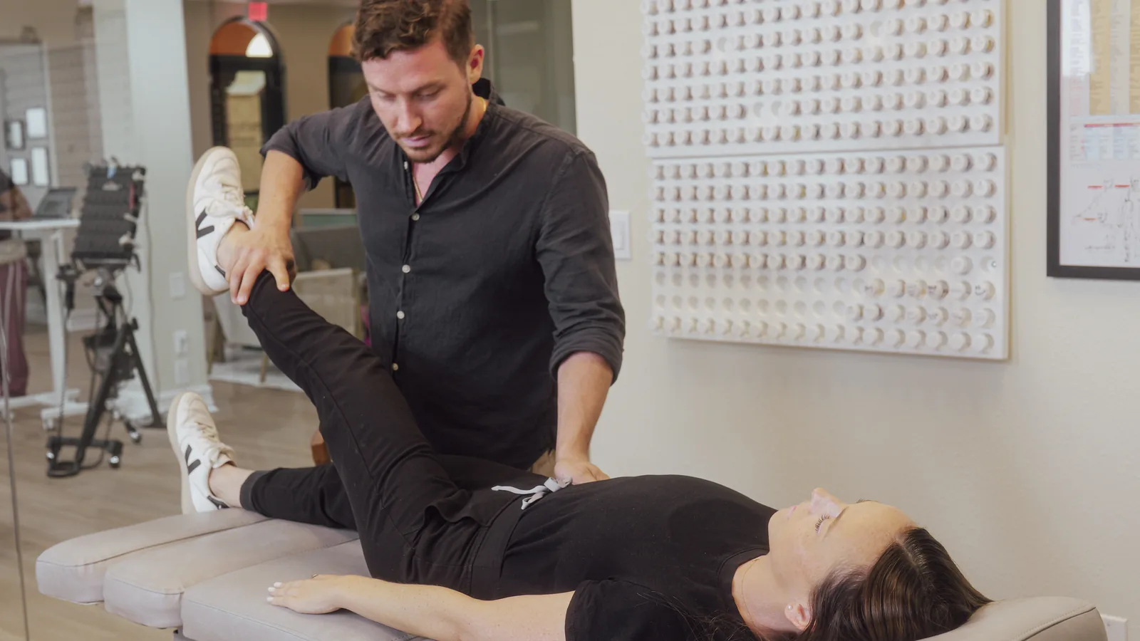 Dr. Jarod Ward muscle testing a patient's leg during applied kinesiology in Fort Myers