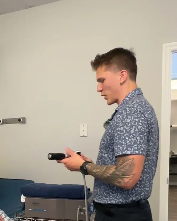 Dr. Gabe Mash with the shockwave therapy handpiece at Crown Chiropractic in Fort Myers, FL